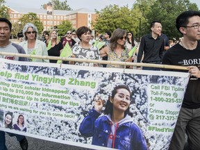 Bingeing Zhang's father Ronggao Zhang, left, and her friend Xiaolin Hou carry the banner as community members join together to walk for Yingying Zhang