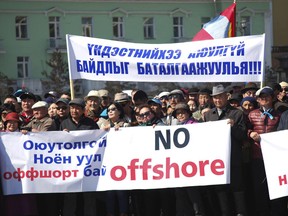 FILE - In this March 31, 2017 file photo, Mongolians hold up banners reading: "Oyu-Tolgoi mine and the Noyon Mountain are in offshore account" and "Let's guarantee security of our nation" during a protest over the alleged theft of government funds deposited in offshore accounts in Ulaanbaatar, Mongolia. Mongolians will vote for a new president on Monday, June 26, 2017 in a race pitting a horse salesman against a former judo star and a nationalist wanting to preserve the vast landlocked country's mineral wealth. (AP Photo/Ganbat Namjilsangarav, File)