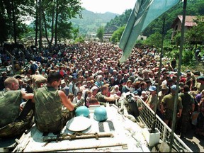 FILE - In this July 13, 1995 file photo, Dutch U.N. peacekeepers sit on top of an armored personnel carrier as Muslim refugees from Srebrenica, eastern Bosnia, gather in the nearby village of Potocari. A Dutch appeals court ruled on Tuesday, June 27, 2017, that the Dutch state is partially liable in the deaths of around 300 Bosnian Muslim men killed by Bosnian Serb army Gen. Ratko Mladic's forces in the 1995 Srebrenica massacre. (AP Photo, File)