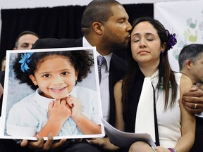 In this Jan. 14, 2013, file photo, Jimmy Greene, left, kisses his wife Nelba Marquez-Greene while holding a portrait of their daughter, Sandy Hook Elementary School shooting victim Ana Marquez-Greene, at a news conference at Edmond Town Hall in Newtown, Conn. Ana Marquez-Greene was one of 26 people killed in a shooting massacre at the school on Dec. 14, 2012, in Newtown, Conn. Nelba Marquez-Greene is among the families of some shooting victims angered by a planned NBC television interview by Megyn Kelly scheduled to air Sunday, June 18, 2017, with Alex Jones, who has claimed the 2012 massacre never happened.