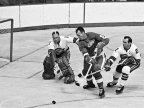 In this Oct. 26, 1967, file photo, California Seals goalie Charlie Hodge, left, knocks the puck away from Detroit Red Wings star Gordie Howe.