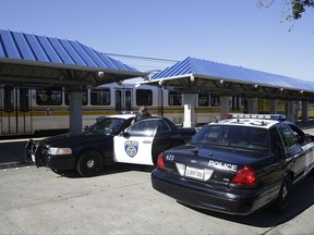 Sacramento Police Officer August Johnson, left, climbs into a patrol car at the Watt Avenue light rail station Wednesday, June 28, 2017, in Sacramento, Calif. A transit deputy was shot in the face Tuesday, at the station, and was taken to a local hospital were he is listed in stable condition. The suspect was arrested later in the evening. (AP Photo/Rich Pedroncelli)