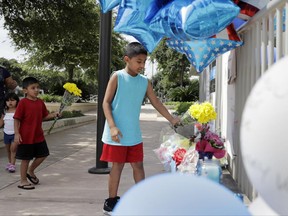 Tony Alameda, right, places flowers at a make-shift memorial at the San Antonio Police headquarters, Friday, June 30, 2017, in San Antonio. Two San Antonio police officers were wounded critically and a suspect was killed in a shootout on a street just north of the city's downtown section. (AP Photo/Eric Gay)