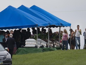 FILE – In this May 3, 2016, file photo, mourners gather around caskets for six of the eight members of the Rhoden family found shot April 22, 2016, at four properties near Piketon, Ohio, during funeral services at Scioto Burial Park in McDermott, Ohio. As part of the investigation into the unsolved slayings of the eight members of the Rhoden family, authorities asked for details Monday, June 19, 2017, on personal or business interactions and conversations that members of the public may have had with four former Ohio residents who once lived near the victims, although none of the four were named as suspects. (AP Photo/John Minchillo, File)