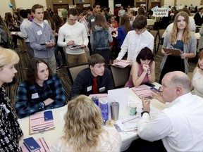 FILE - In this Wednesday, April 5, 2017, file photo, volunteer Kurt Kern, lower right, a financial adviser at Ameriprise Financial, explains different options for savings and investments to a group of high school seniors during the Eau Claire Area Chamber of Commerce's Real Life Academy at the Lismore Hotel in Eau Claire, Wis. Students from six area high schools that have completed a personal finance class participate in the Real Life Academy to learn money management skills in a hands-on setting. Teaching teens the basics of saving, following a budget and the principles behind responsibly managing checking and credit accounts can instill healthy financial habits that will serve them well as adults. (Marisa Wojcik/The Eau Claire Leader-Telegram via AP, File)