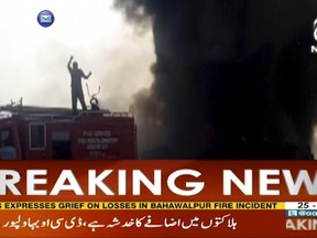 In this image taken from video, black smoke rises from oil tanker on road in Bahawalpur, Pakistan, Sunday,  June 25, 2017.  An overturned oil tanker burst into flames in Pakistan on Sunday, killing people who had rushed to the scene of the highway accident to gather leaking fuel, an official said. (AAJ News via AP Video)