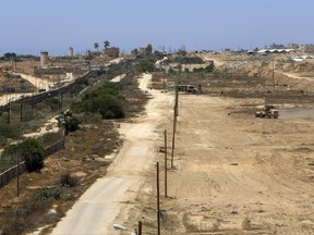 A bulldozer works on creating a buffer zone along the Egyptian border with the Gaza strip, near Egyptian army watch towers, left, and near smuggling tunnels, right, in Rafah, Wednesday, June 28, 2017. The Hamas-run Interior Ministry said Wednesday the creation of a 12-kilometer-long (7.5-mile) corridor 100 meters (330 feet) wide was agreed upon in recent face-to-face negotiations with Egyptian officials and is part of the Islamic militant group's efforts to combat extremists and improve ties with Cairo. (AP Photo/Adel Hana)