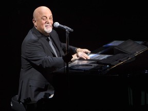 FILE - In this April 5, 2017 file photo, Billy Joel performs in concert for the grand re-opening of the Nassau Coliseum in Uniondale, N.Y.  Fifty years after he finished short by one English class credit from graduating high school,  Joel is returning to his Long Island hometown to speak at this weekend's commencement ceremony. The Rock and Roll Hall of Famer will be among the speakers at Saturday, June 24 graduation for Hicksville High School's Class of 2017. (Photo by Scott Roth/Invision/AP, File)