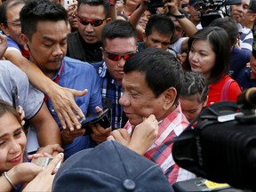 FILE - In this Monday, May 9, 2016, file photo, a supporter pinches the cheek of then front-running presidential candidate Mayor Rodrigo Duterte as he leaves a local high school in Matina district, his hometown, after voting in Davao city in southern Philippines. It's been a remarkably turbulent first year for Duterte, whose war on drug has left thousands of suspects dead and prompted critics to call his rule a "human rights calamity." (AP Photo/Bullit Marquez, file)