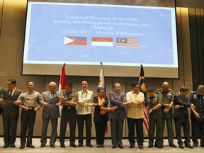 Philippine Foreign Affairs Secretary Alan Peter Cayetano (seventh from left), Indonesian Foreign Minister Retno Marsudi (eight from left), Malaysian Foreign Minister Anifah Haji Aman (Ninth from left), as well as their respective armed forces and police chiefs, link arms prior to the start of their Trilateral Security Meeting in Pasay City, Manila, Philippines, Thursday, June 22, 2017. The southeast asian neighbors plan to closely cooperate to halt the flow of militants, weapons, funds and extremist propaganda across their borders as they expressed alarm over the recent attacks in their countries, including the disastrous siege of southern Marawi city by militants aligned with the Islamic State group. (AP Photo/Bullit Marquez)