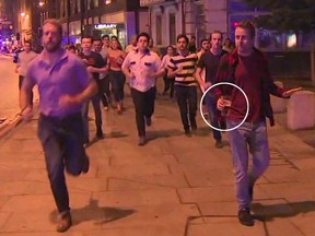 In this image taken from video footage, people run from the scene of attack, alongside a man strolling holding a pint of beer, right, in London, late Saturday, June 3, 2017.