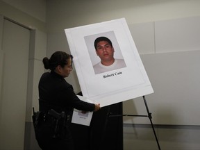 Los Angeles police officer Liliana Preciado sets up a display board showing an images of officer Robert Cain in preparation for a news conference Thursday, June 22, 2017, in Los Angeles. Cain has been arrested for allegedly having sex with a 15-year-old cadet who's suspected of joyriding in stolen patrol cars. (AP Photo/Jae C. Hong)
