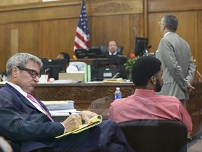 Dominique Heaggan-Brown, right, and his attorney Jonathan C. Smith, left, watch the power point presentation of use of force expert, Robert C. Willis on a video screen during the trial of former Milwaukee officer Heaggan-Brown  Monday, June 19, 2017,  in Milwaukee. A police expert in the use of deadly force says on Monday that Heaggan-Brown, on trial for fatally shooting a black man after a foot chase "acted in accordance with his training." Attorney Steven R. Kohn is at upper right. (Michael Sears/Milwaukee Journal-Sentinel via AP, Pool)