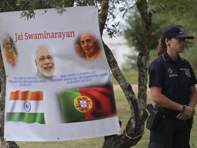 A police officer stands by a welcome poster for India's Prime Minister Narendra Modi at the Radha Krishna Temple before his visit in Lisbon, Portugal, Saturday June 24, 2017. Modi is on a one day visit to Portugal. (AP Photo/Armando Franca)