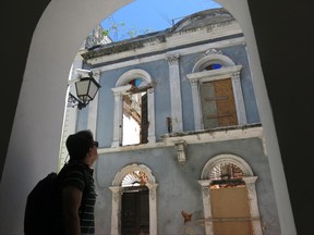 In this June 22, 2017 photo, architect Andy Rivera looks up at an abandoned building in the historic part of Puerto Rico's capital, in San Juan, Puerto Rico. The U.S. territory's prized historic buildings are falling apart as a debt crisis and enduring economic recession have slashed public and private funding for maintenance, repairs and restoration. (AP Photo/Danica Coto)