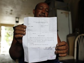 Elvis Guzman shows an order to show cause from a bankruptcy judge while standing in his home in San Juan, Puerto Rico, Tuesday, June 20, 2017. When the 59-year-old who sells recycled metal for a living, received another letter from the back he figured it was a warning to his family that they were behind on their mortgage payments. An attorney translated the letter written in English. "He told me I was losing my home. When he told me that, I burst into tears," Guzman recalled. (AP Photo/Ricardo Arduengo)