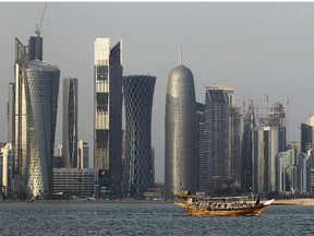 In this Thursday Jan. 6, 2011 file photo, a traditional dhow floats in the Corniche Bay of Doha, Qatar, with tall buildings of the financial district in the background.