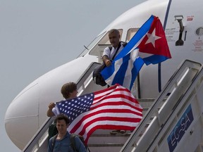 In this Aug. 31, 2016 file photo, two passengers deplane from JetBlue flight 387 waving a United States, and Cuban national flag, in Santa Clara.