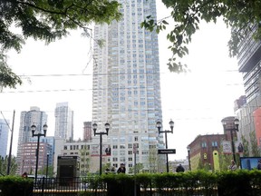 A luxury 50-story residential tower at 65 Bay Street built by Kushner Companies and its partners, in the background, is in a booming waterfront district in Jersey City. Passengers await a train at a nearby light rail station.