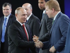 Russia's President Vladimir Putin shakes hands with Myron Brilliant, executive vice president and head of International Affairs at the U.S. Chamber of Commerce on Friday in St. Petersburg.