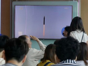 People at a Seoul train station watch a TV news program showing a file image of a missile launch by North Korea, at Seoul Railway Station on Thursday.