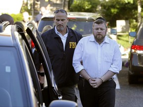 Shimon Nussbaum is taken to a police vehicle after he and and his wife and Yocheved Nussbaum were arrested Monday, June 26, 2017,  in connection with a public-assistance fraud scheme in Lakwood, N.J. Their arrest was part of a larger operation, led by federal and state authorities, that netted the arrests of six others. (Peter Ackerman/The Asbury Park Press via AP)
