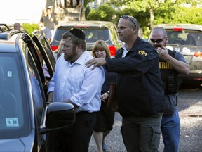Shimon,  left, and Yocheved (behind) Nussbaum are arrested Monday, June 26, 2017, in connection with a public-assistance fraud scheme, in Lakewood, N.J. Their arrest was part of a larger operation, led by federal and state authorities, that netted the arrests of six others. (Peter Ackerman/The Asbury Park Press via AP)