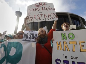 Marilia Frutuoso, center, joins other protesters outside the Federal Courthouse to protest a new Texas "sanctuary cities" bill that aligns with the president's tougher stance on illegal immigration, Monday, June 26, 2017, in San Antonio. (AP Photo/Eric Gay)