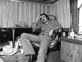 FILE - In this Sept. 23,1976 file photo Burt Reynolds sits in his trailer on the set of "Smokey and the Bandit," in Atlanta.   Hundreds of fans in Trans Ams made it to Atlanta to celebrate the 40th anniversary of "Smokey and the Bandit." About 350 cars retraced actor Burt Reynolds' wild ride from the Texas-Arkansas line to Atlanta in the movie that roared into pop culture in 1977. (Atlanta Journal-Constitution via AP)