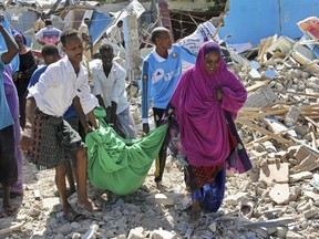 Somalis carry away the body of a civilian who was killed in a car bomb attack in Mogadishu, Somalia Tuesday, June 20, 2017. A number of people are dead after a suicide car bomber in a vehicle posing as a milk delivery van detonated at a district headquarters in Somalia's capital, police said Tuesday. (AP Photo/Farah Abdi Warsameh)