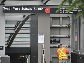 An MTA worker sweep outside the doorway of a "flood door" leading to the No. 1 train South Ferry subway station, Tuesday June 27, 2017, in New York. The station reopened Tuesday, nearly five years after it was flooded by Superstorm Sandy in October 2012.  (AP Photo/Bebeto Matthews)