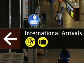 Travelers walk near a sign for international arrivals at the Seattle-Tacoma International Airport, Monday, June 26, 2017, in Seattle. The U.S. Supreme Court said Monday that President Donald Trump's travel ban on visitors from Iran, Libya, Somalia, Sudan, Syria and Yemen can be enforced if those visitors lack a "credible claim of a bona fide relationship with a person or entity in the United States," and that justices will hear full arguments in October 2017. (AP Photo/Ted S. Warren)