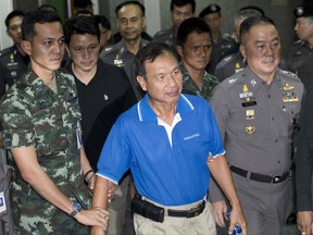 Wattana Pumret, 61, is escorted by officials as he arrives at police headquarters for a press conference in Bangkok, Thailand, Tuesday, June 20, 2017. Wattana, who was arrested for the bombing of an army hospital in Bangkok, says he carried out the attack that wounded 21 people to symbolize defiance against Thailand's ruling military junta. (AP Photo/Sakchai Lalit)