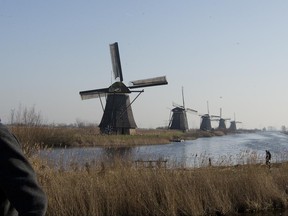 FILE - In this Feb. 14, 2017, file photo, tourists walk by windmills lining Hooge Boezem van de Overwaard canal at the Unesco World Heritage site in Kinderdijk, Netherlands. (AP Photo/Peter Dejong, File)