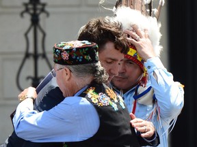 ADDS ID OF MAN HUGGING TRUDEAU Prime Minister Justin Trudeau receives a hug Clement Chartier, President of the Métis National Council, as Perry Bellegarde, national chief of the Assembly of First Nations, right, looks on during National Indigenous Peoples Day celebrations in Ottawa on Wednesday, June 21, 2017. THE CANADIAN PRESS/Sean Kilpatrick