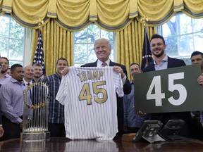President Donald Trump holds a Chicago Cubs jersey as he meets with members of the 2016 World Series Champions Chicago Cubs, Wednesday, June 28, 2017, in the Oval Office of the White House in Washington. Cubs third baseman Kris Bryant holds a "45" sign. (AP Photo/Susan Walsh)