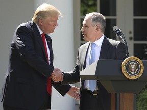 FILE - In this June 1, 2017 file photo, President Donald Trump shakes hands with EPA Administrator Scott Pruitt after speaking about the U.S. role in the Paris climate change accord in the Rose Garden of the White House in Washington. A new poll finds that less than a third of Americans support President Donald Trump's decision to withdraw from the Paris climate accord, with just 18 percent of respondents agreeing with his claim that pulling out of the international agreement to reduce carbon emissions will help the U.S. economy. (AP Photo/Andrew Harnik, File)