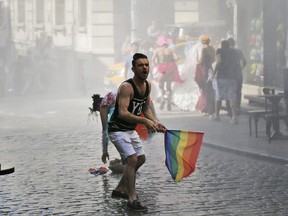 FILE - In this Sunday, June 28, 2015 file photo, a participant of the Pride Week march in Istanbul, reacts as others flee after Turkish police use a water canon to disperse them. For several years, Pride Week in Istanbul attracted tens of thousands of participants, making it one of largest gatherings celebrating gay, lesbian and transgender rights and diversity in the Muslim world. That changed suddenly in 2015, when authorities, citing security concerns, banned gay and trans-gender pride events chasing away shocked participants trying to converge on central Taksim Square with tear gas and water cannons. (AP Photo/Emrah Gurel, File)