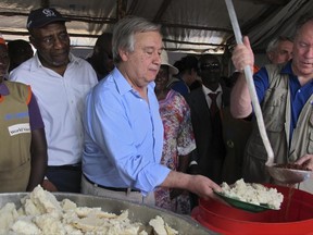 United Nations Secretary-General Antonio Guterres, center, serves maize meal to refugees in the food distribution tent of the Imvepi reception center for South Sudanese refugees in northern Uganda, Thursday, June 22, 2017. Guterres visited ahead of a U.N.-backed summit in Uganda that is aimed at raising global awareness of the world's fastest-growing refugee crisis and urged South Sudan's leaders to end a civil war that has killed tens of thousands and displaced millions of people. (AP Photo/Rodney Muhumuza)