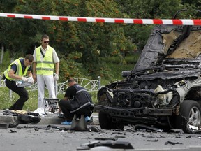 Forensic experts examine the wreckage of a  car in Kiev, Ukraine, Tuesday, June 27, 2017. Ukrainian authorities say that a senior military intelligence officer has been killed in a car bomb in the country's capital. Police say that the driver of a luxury car has been killed instantly as the vehicle blew up at a Kiev intersection. (AP Photo/Sergei Chuzavkov)