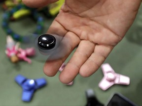 FILE - In this May 11, 2017, file photo, Funky Monkey Toys store owner Tom Jones plays with a fidget spinner in Oxford, Mich. Fidget spinners are among the those on the annual list of hazardous summer toys compiled by World Against Toys Causing Harm, Inc., a nonprofit consumer watchdog. (AP Photo/Carlos Osorio, File)