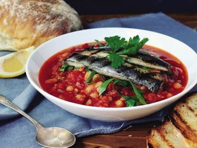 Grilled sardines top a tomato and sausage stew in this dish from Newfoundland dish.