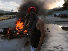 An anti-government demonstrator stands by a burning motorcycle protesters took away from National Guards who blocked them from marching to the office of Attorney General Luisa Ortega Diaz to show support for the one-time government loyalist, in Caracas, Venezuela, Thursday, June 22, 2017. Venezuela's Supreme Court cleared the way for the prosecution of the country's chief prosecutor, who became a surprise hero to the opposition after breaking ranks with the government of President Nicolas Maduro over his efforts to concentrate power. (AP Photo/Fernando Llano)