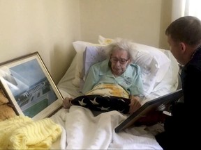 In this image taken from video provided by Stringr, Captain Zacharia Fike of Purple Hearts Reunited presents a flag and Purple Heart to Mildred Stotzer at the Sunrise of Westfield assisted living facility in Westfield, N.J., Wednesday, June 28, 2017. The flag and medals belonged to Stotzer's brother, Master Sgt. Frederick Boelzle, was killed in Belgium in December 1944. (Stringr via AP)