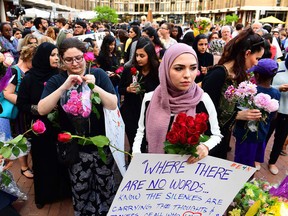 Hiba Isneail, left, and Isra Chaker, brought signs and help hand out flowers as they attend a vigil for Nabra Hassanen