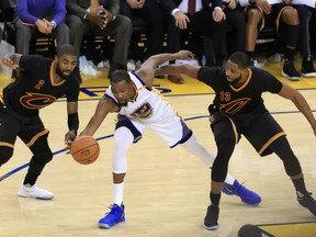 Kevin Durant, middle, of the Golden State Warriors maintains possession despite being defended by two members of the Cleveland Cavaliers during Game 2 action in the NBA Finals Sunday in Oakland. Durant had 33 points as the Warriors posted a 132-113 win to take a 2-0 lead in the best-of-seven series. Game 3 is Wednesday in Cleveland.