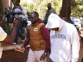 Zimbabwean Pastor Evan Mawarire, centre, arrives at court handcuffed with an unidentified person in Harare, Wednesday, June, 28, 2017.  The anti government activist pastor Mawarire was detained Monday for addressing protesting university students, and appeared in court charged with disorderly conduct to be freed on bail Wednesday. (AP Photo/Tsvangirayi Mukwazhi)