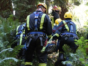 Surrey firefighters had to perform a low angle rescue after a woman was found at the bottom of Delta Creek off 97th Ave & 117B St on the afternoon of Tuesday, July 4.  A neighbour heard her screams and hiked down and located her and called 9-1-1. She reported that she had been down there since Thursday evening, She was transported to hospital with non life threatening injuries including dehydration and several cuts & bruises. Photos by Shane MacKichan. [PNG Merlin Archive]