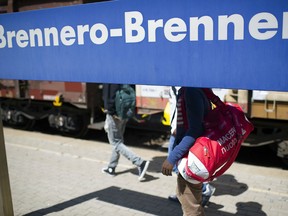Alex (L), a 28-year-old from Ethiopia and 19-year-old Abel (C) walk on a plattform towards a train to Innsbruck, Austria, at the Brenner Pass at the Austrian border on 21 July, 2015, in Bolzano, Italy