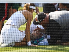 Bethanie Mattek-Sands receives treatment from the medical team and during her second-round match against Sorana Cirstea (kneeling, left) on July 6, 2017.